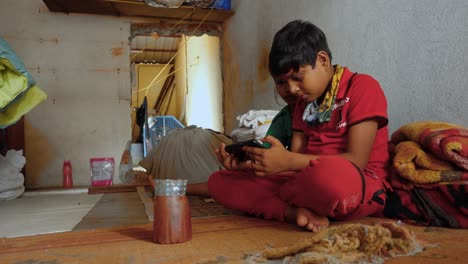 Young-Indian-Boy-and-Sister-Sit-Absorbed-in-Online-Streaming-Video-on-Smartphone