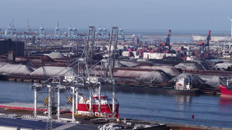 Industrial-container-cranes-and-anchored-freight-ship-in-Rotterdam-port---aerial