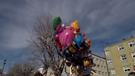 Group-Of-Colourful-Cartoon-Helium-Balloons-Held-By-Seller-In-Ordes,-Spain