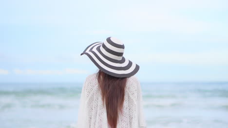 Back-View-of-Woman-With-Long-Hair-and-Floppy-Hat-Standing-in-Front-of-Sea-Waves-and-Horizon,-Slow-Motion