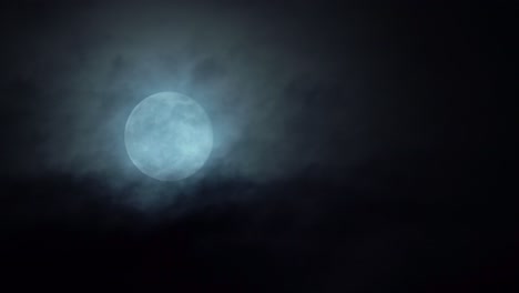 Bright-white-full-moon-rising-in-the-sky---Dark-mystical-clouds-passing-in-front-while-moon-slowly-moving-upwards-in-frame