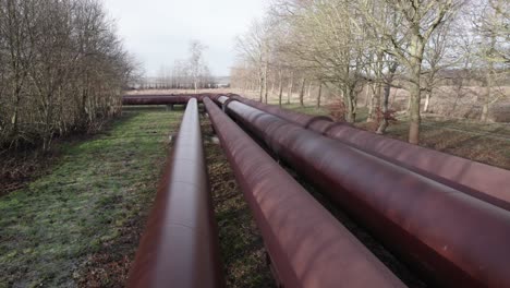 Following-Industry-Pipes,-Water-Cooling-Piping-in-a-Grey-Landscape---Dolly-In-Shot