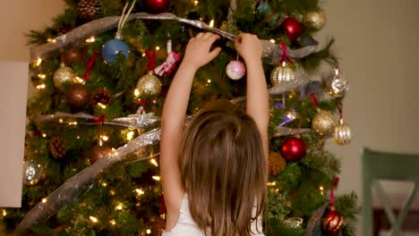 Little-girl-hanging-ornaments-on-a-Christmas-tree