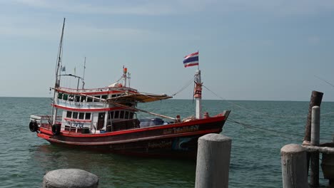 Ein-Fischerboot,-Das-Sich-Mit-Der-Welle-Bewegt,-Mit-Wehender-Flagge,-Angedockt-Am-Fischerdock-Von-Pattaya,-Chonburi,-Thailand