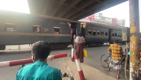Train-passing-at-a-level-crossing-while-rickshaw-pullers-and-people-stopped-and-waiting-for-the-train-to-pass