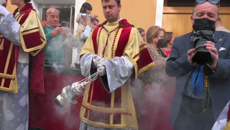 A-man-swings-a-censer-burning-incense-to-clear-the-way-during-a-Holy-Week-procession-in-Cadiz,-Spain