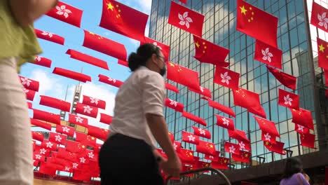 Pedestrians-cross-the-street-as-flags-of-the-People's-Republic-of-China-and-the-Hong-Kong-SAR-are-displayed-ahead-of-July-1st-anniversary-of-Hong-Kong's-handover-to-China-in-Hong-Kong