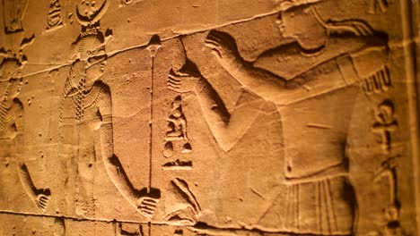 Details-of-hieroglyphs-litten-by-artificial-light-inside-the-temple-of-Philae,-Aswan,-Egypt