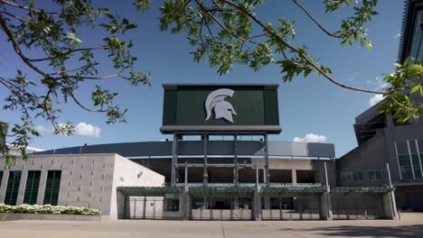 Exterior-of-Spartan-Stadium-on-the-campus-of-Michigan-State-University-in-East-Lansing,-Michigan-with-slow-motion-pan-left-to-right-showing-trees