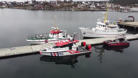 Three-generations-of-SAR-Rescue-boats-from-Redningsselskapet-company---Aerial-rotating-around-boats-in-Lillesand-marina-Norway