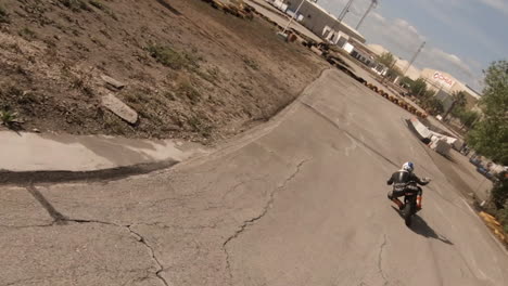 Motorcyclist-in-leather-leans-into-tight-corner,-filmed-by-FPV-above