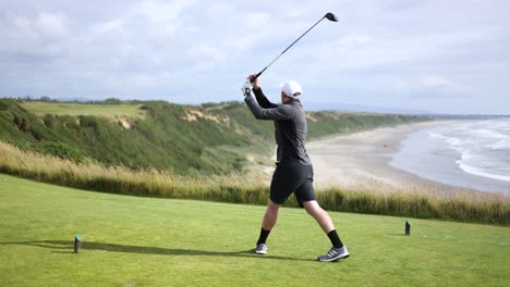 Männlicher-Golfer-Auf-Schwingendem-Golfschläger-Auf-Abschlagbox-Mit-Wunderschönem-Meereshintergrund