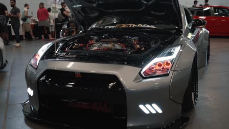 Arc-Shot-of-a-Silver-Nissan-GTR-with-Lights-On-at-Driven-Auto-Show