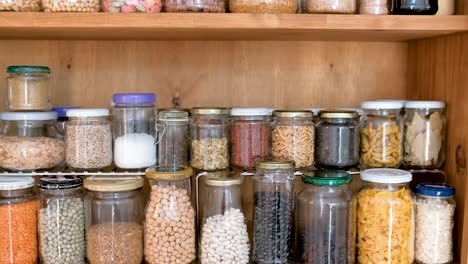 Jars-of-spices-and-cereals-in-kitchen-cupboard,-pull-back-reveal