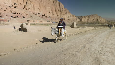 Afghanischer-Einheimischer-Reitet-Mit-Seinem-Sohn-An-Einem-Sonnigen-Tag-In-Bamyan,-Afghanistan,-Auf-Einem-Esel