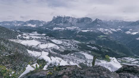 Mountain-timelapse-with-nearby-village-covered-in-snow-during-spring