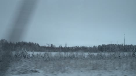 Log-cabin-and-snowy-forest-landscape-from-car-window,-POV-shot
