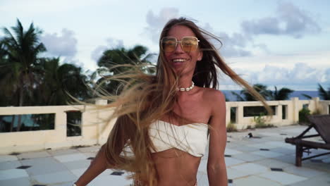 Beautiful-woman-with-white-bikini-and-sunglasses-spinning-with-long-hair