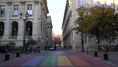 Regenbogenfarbener-Fußgängerüberweg-Mit-Einem-Mann,-Der-Darüber-Läuft,-Und-Menschen,-Die-Sich-Den-Stolzfarben-Nähern,-Handgeführte-Halbtotalaufnahme