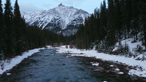 Creek-in-mountain-forest-bridge--downstream-reveal-winter