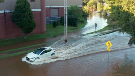 White-car-drives-into-flooded-street-water