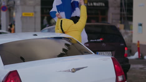 Person-waving-a-Flag-out-from-car-windows,-celebrating-Olympic-Ice-hockey-championship,-in-Helsinki,-Finland