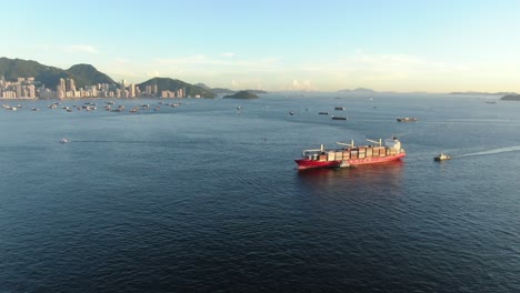 Large-Container-Ship-leaving-Hong-Kong-bay-under-Stonecutters-bridge,-Aerial-view