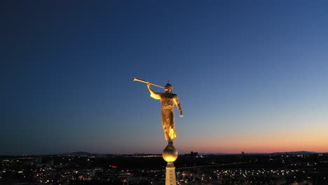 Close-up-aerial-view-of-Angel-Moroni-on-the-Ogden-Utah-Temple-of-the-Mormon-Church-against-blue-night-sky-and-city-lights