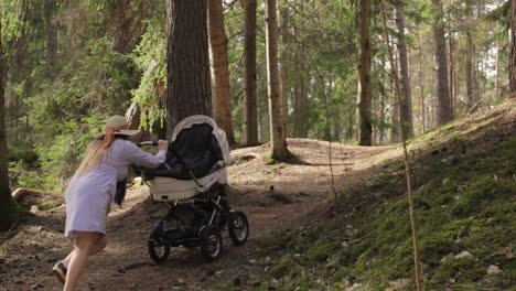 Junge-Mutter-Kämpft-Darum,-Den-Kinderwagen-Im-Finnischen-Wald-Bergauf-Zu-Tragen
