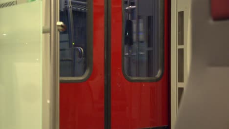 Red-transit-train-doors-and-passing-night-scenery-through-windows