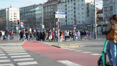 Handheld-shot-of-pedestrians-crossing-the-street-on-a-crosswalk-while-cars-are-passing-by
