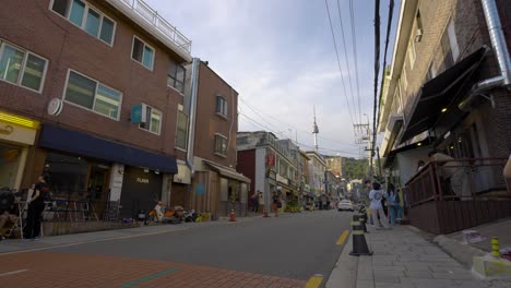 Modern-Yongsan-Haebangchon-Village-street-with-numerous-western-restaurants-and-shops-and-view-of-landmark-N-Seoul-Namsan-Tower-at-sunset---wide-establishing-shot