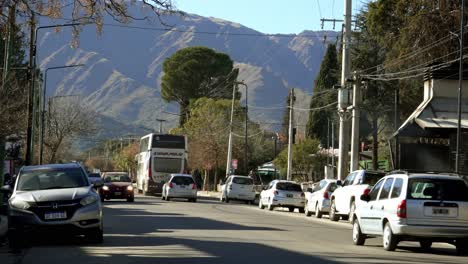 Vista-De-La-Avenida-Del-Sol-Con-Autos-Pasando-Y-Las-Montañas-Comechingones-Detrás-En-Un-Día-Soleado