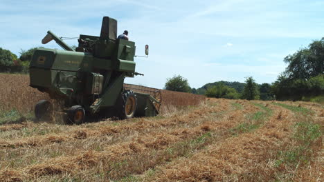 Old-combine-harvester-on-a-small-farm-harvesting-barley-in-a-field