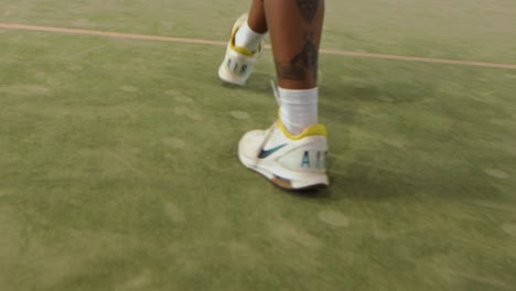 Man-with-tattoos-and-Nike-shoes-walks-out-on-a-padel-court---slow-motion