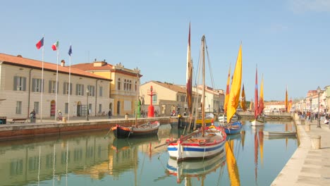 Pan-shot-of-museum-of-boats-in-the-Porto-Canale-Leonardesco-of-Cesenatico,-Emilia-Romagna,-Italy-with-tourists-walking-around-at-daytime
