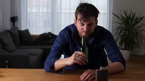 Medium-shot-of-a-young-hangover-man-drinking-beer-at-home-in-modern-apartment