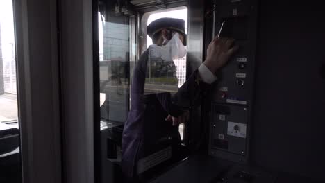 Train-conductor-wearing-facemask-looking-outside-as-train-drives-into-station