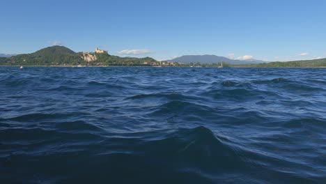 Vista-De-ángulo-Bajo-A-Nivel-De-Superficie-De-Un-Pequeño-Bote-Navegando-En-El-Lago-Maggiore-En-Italia