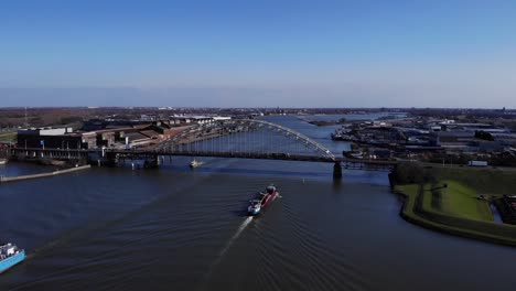 Aerial-View-Of-Arch-Bridge-With-Barge-Sailing-At-Noord-River-Under-Bright-Blue-Sky-In-South-Holland,-Netherlands