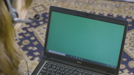 Woman-talking-online-in-green-screen-laptop