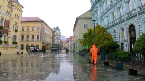 City-Cleaner-Walking-a-Pedestrian-Street-in-Celje,-Slovenia-a-Rainy-Morning