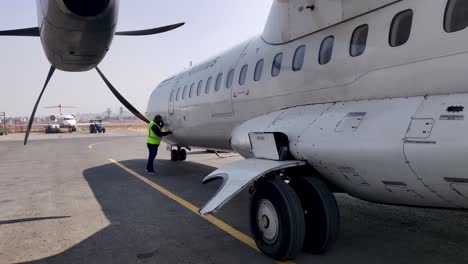 Ground-staff-examines-cargo-door-of-a-turbo-prop-aircraft-parked-on-the-apron