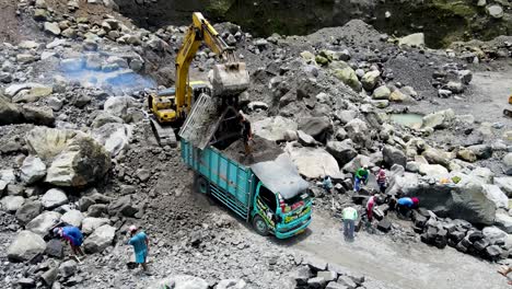 Excavator-loading-and-filtrating-volcanic-sand-to-dump-truck-in-open-pit-mine