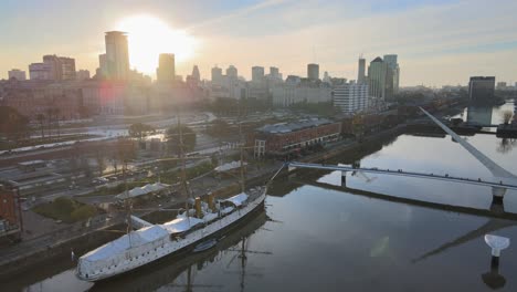 Aerial-of-famous-bridge,-old-ship-and-Buenos-Aires-skyline-at-sunset