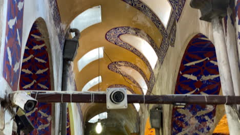 Tilt-clip-down-from-ornate-ceiling-to-narrow-thoroughfare-of-the-Grand-Bazaar-in-Istanbul