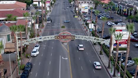 Aerial-on-Ventura-Blvd,-famous-Encino-Commons-sign,-palm-trees-on-side-of-street