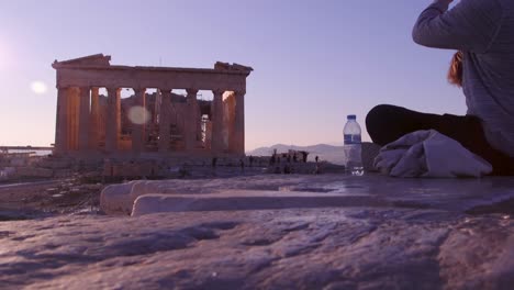A-tourist-drinks-a-bottle-of-water-at-sunset-near-the-parthenon