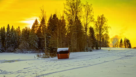 Yellow-sky-snow-forest-landscape-with-campfire-and-barrel-sauna