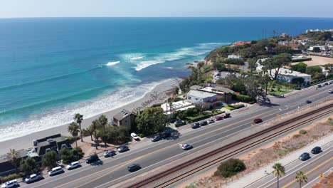 Drone-shot-flying-over-a-road-leading-to-a-beautiful-beach-in-Encinitas,-California
